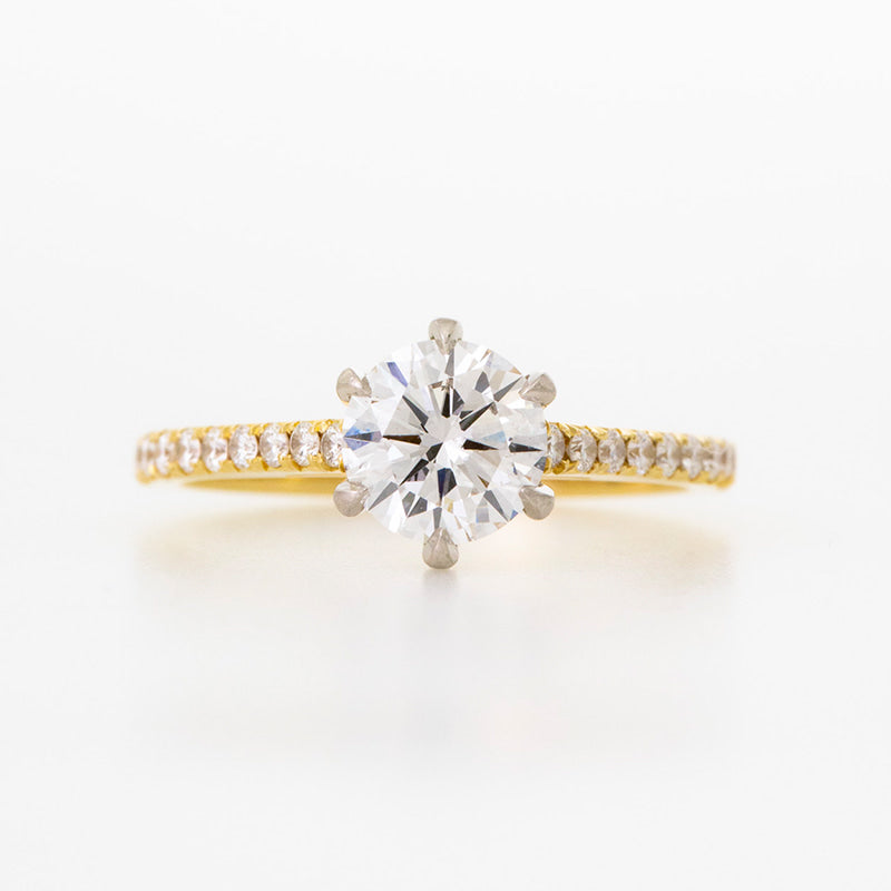 Six prong, round brilliant diamond engagement ring set in Platinum with yellow gold shank diamond set to the half eternity style in french pave.