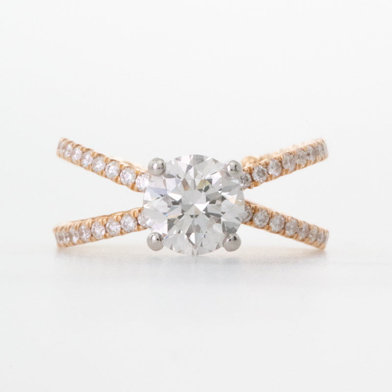 Platinum and rose gold anniversary engagement ring  featuring a one carat round brilliant diamond with full eternity diamond setting on criss cross shank. Rope textured inside criss cross shank to commemorate ten year anniversary.