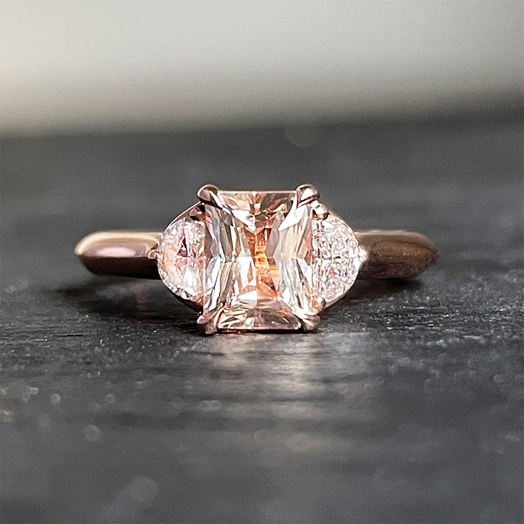 https://modernlovejewellery.com/cdn/shop/products/MLJ-peachy-keen-on-you-14k-rose-gold-peach-sapphire-half-moon-diamonds-engagement-ring-front-view_1600x.jpg?v=1638553686